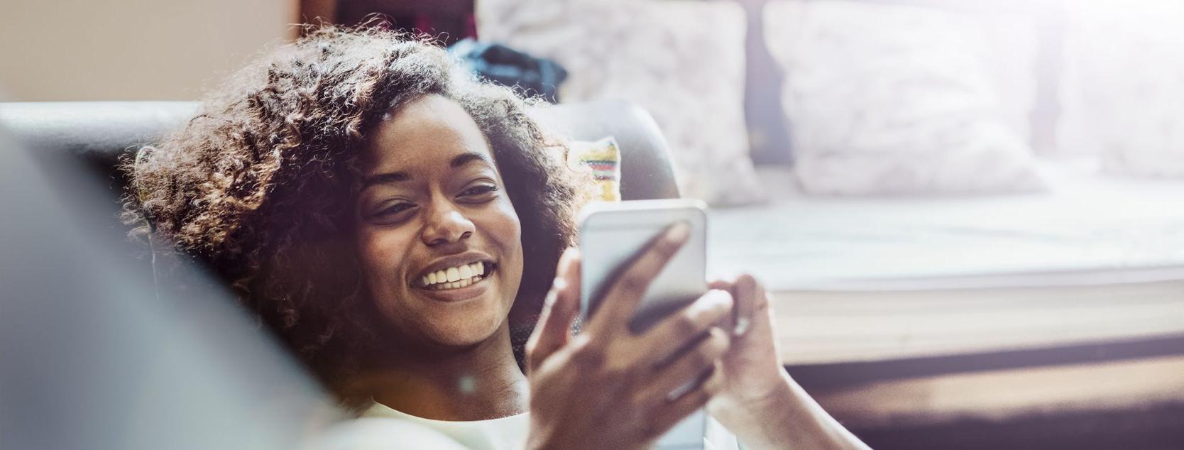 A woman lounges as she checks her Patelco account balance on her phone.